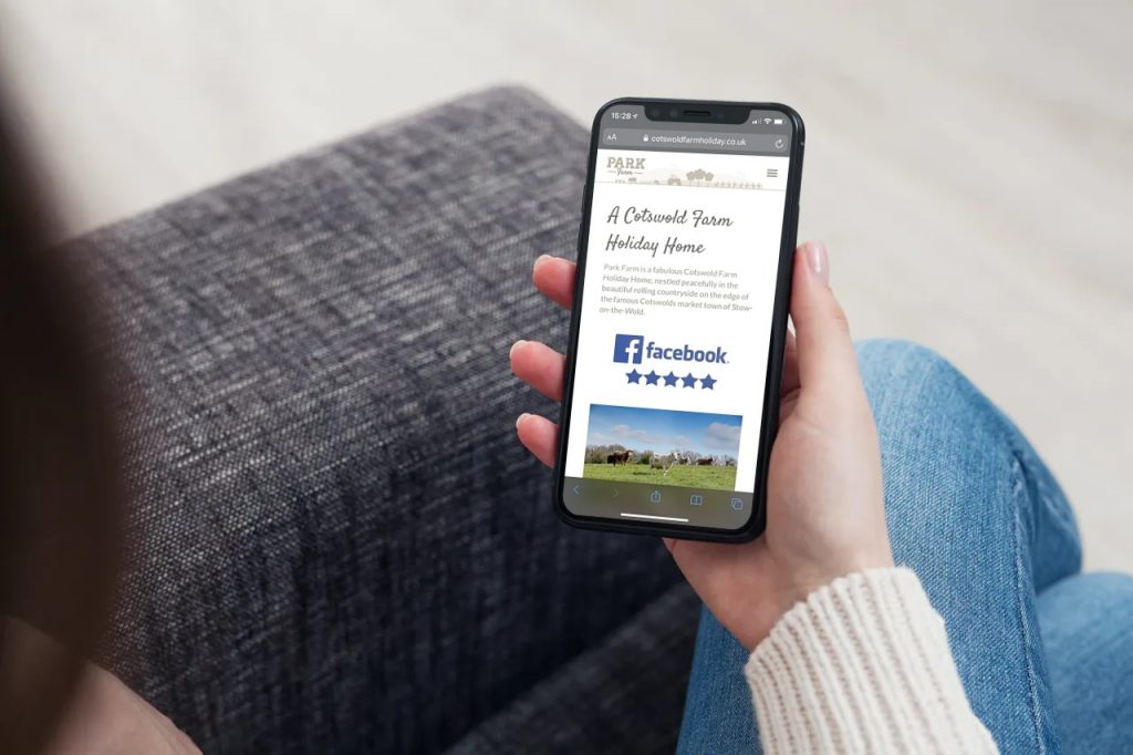 A lady holding a mobile with the Park Farm website on the screen.